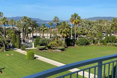 a balcony with a view of a park with palm trees at REF 843 - Cannes Croisette - Sea view apartment for rent in Cannes