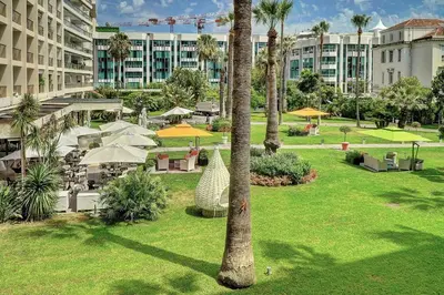 a park with palm trees and tables and umbrellas at REF 1434 - Cannes Croisette - Sea view apartment for rent in Cannes