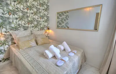 a bedroom with a bed with white pillows and a mirror at Cannes centre rue d'antibes et palais in Cannes