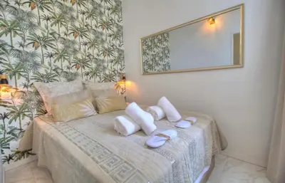 a bedroom with a bed with white pillows and a mirror at Cannes centre rue d'antibes et palais in Cannes