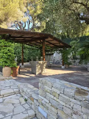 a patio with a stone wall and a wooden pavilion at 1-Bedroom guesthouse with pool access in Cannes