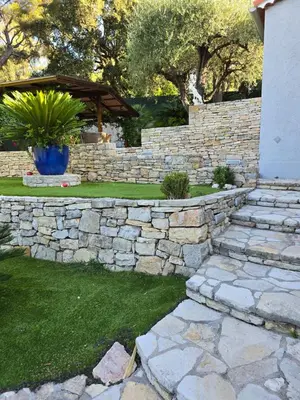 a stone retaining wall with a stone walkway at 1-Bedroom guesthouse with pool access in Cannes