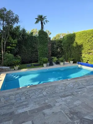 a swimming pool in a yard with a hedge at 1-Bedroom guesthouse with pool access in Cannes