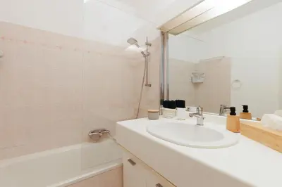 a white bathroom with a sink and a tub at Appartement Grand Balcon Sud avec Piscine proche Cannes in Le Cannet