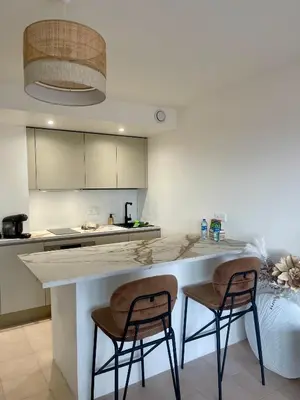 a kitchen with a counter and two bar stools at Appartement Grand Balcon Sud avec Piscine proche Cannes in Le Cannet