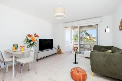 a living room with a couch and a television at Appartement Grand Balcon Sud avec Piscine proche Cannes in Le Cannet