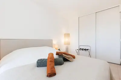 a bedroom with a white bed with towels on it at Appartement Grand Balcon Sud avec Piscine proche Cannes in Le Cannet