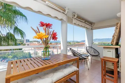 a living room with a couch and a table and a tv at Appartement Grand Balcon Sud avec Piscine proche Cannes in Le Cannet