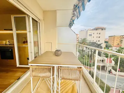 a balcony with a wooden table and a view of a city at B020- Elegante et lumineux a deux pas plages et centre in Cannes