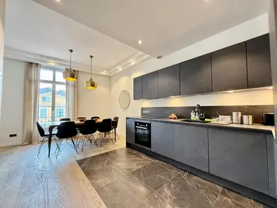 a kitchen with black cabinets and a table and chairs at Carré d'Or - Luxueux - Vue mer in Cannes