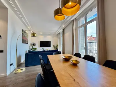 a dining room with a table and a blue couch at Carré d'Or - Luxueux - Vue mer in Cannes