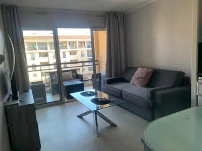 a living room with a couch and a table at 2 pièces vue piscine et plage à 2min in Cannes