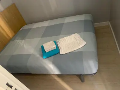 a bed with a blue foot board with two towels on it at 2 pièces vue piscine et plage à 2min in Cannes
