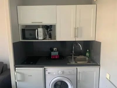 a kitchen with a washing machine and a microwave at 2 pièces vue piscine et plage à 2min in Cannes