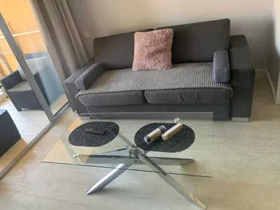 a living room with a couch and a glass table at 2 pièces vue piscine et plage à 2min in Cannes