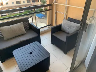 a balcony with a couch and a chair and a table at 2 pièces vue piscine et plage à 2min in Cannes