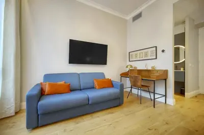 a blue couch with orange pillows in a living room at Belétage - 5BDR - 4 Bath - Cannes Center - Garage and AC in Cannes