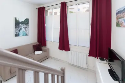 a living room with red curtains and a tv at Modern 2 Rooms in the heart of Cannes in Cannes