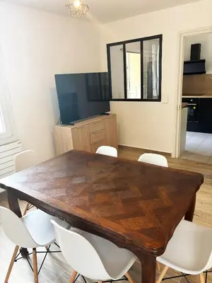 a dining room with a wooden table and white chairs at Villa cannoise en bord de mer in Cannes