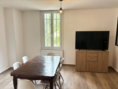 a dining room with a table and a flat screen tv at Villa cannoise en bord de mer in Cannes