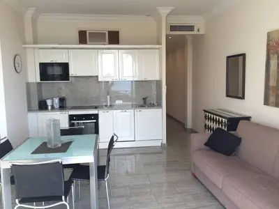 a kitchen and living room with a table and a couch at Cannes La Croisette - Studio face mer avec chambre cabine et balcon in Cannes