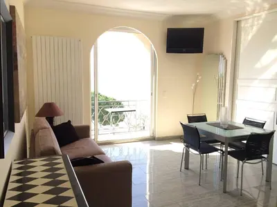 a living room with a couch and a table with chairs at Cannes La Croisette - Studio face mer avec chambre cabine et balcon in Cannes