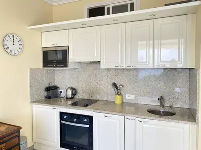 a kitchen with white cabinets and a clock on the wall at Cannes La Croisette - Studio face mer avec chambre cabine et balcon in Cannes