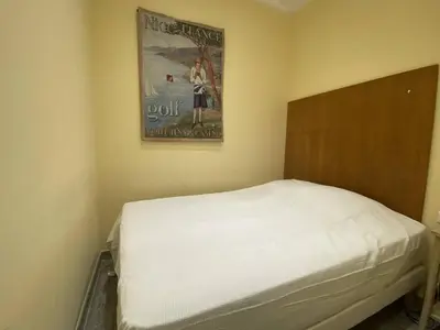 a bed in a room with a poster on the wall at Cannes La Croisette - Studio face mer avec chambre cabine et balcon in Cannes