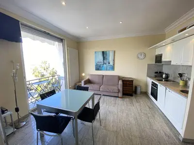a kitchen and living room with a table and a couch at Cannes La Croisette - Studio face mer avec chambre cabine et balcon in Cannes