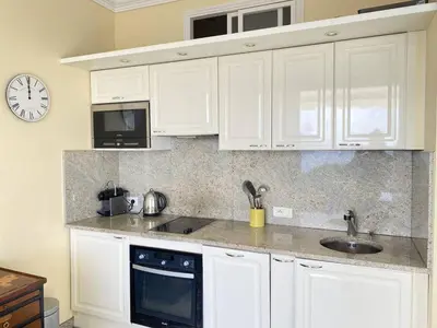 a kitchen with white cabinets and a clock on the wall at Cannes La Croisette - Studio face mer avec chambre cabine et balcon in Cannes
