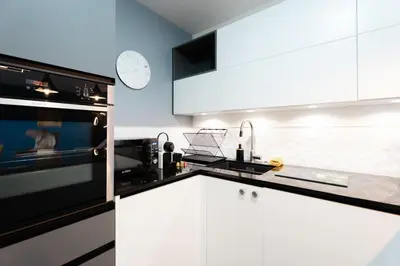 a kitchen with white cabinets and black appliances at Elégant 3 pièces avec Terrasse - Centre - Lumineux in Cannes
