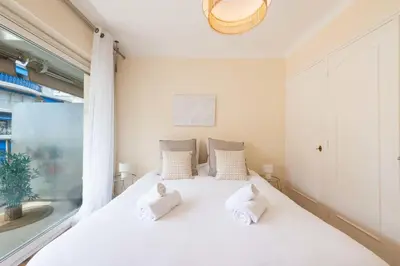 a white bed in a room with a window at 1-Br with Terrace Palm Beach Close to Beaches in Cannes