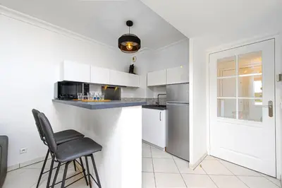 a kitchen with white cabinets and a black chair at Joli deux pièces - Quartier Pointe Croisette - EC in Cannes