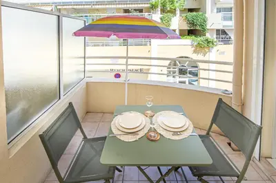 a table and chairs on a balcony with an umbrella at Joli deux pièces - Quartier Pointe Croisette - EC in Cannes