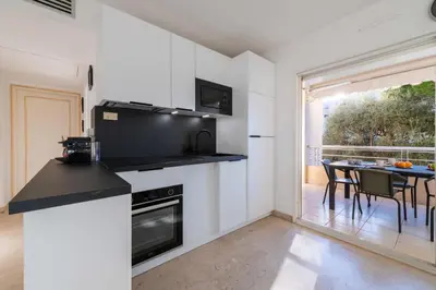 a kitchen with white walls and a table with chairs at 2-Br Apartment Residence with Pool Near La Croisette in Cannes