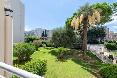 a balcony with a yard with a palm tree at 2-Br Apartment Residence with Pool Near La Croisette in Cannes