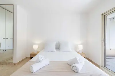 a white bedroom with a large bed with white pillows at 2-Br Apartment Residence with Pool Near La Croisette in Cannes