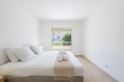 a white bedroom with a large bed and a window at 2-Br Apartment Residence with Pool Near La Croisette in Cannes