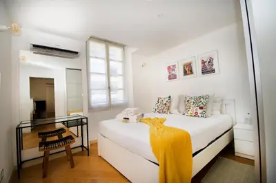 a white bedroom with a bed and a mirror at Princess Victoria Standing Presta in Cannes