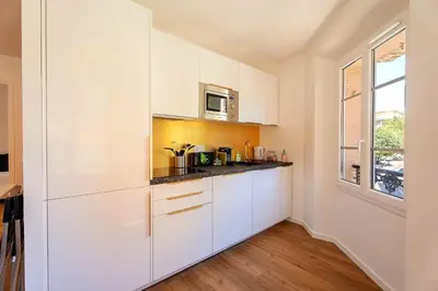a white kitchen with white cabinets and a window at 3 Chambres - Central - Plage à 10 min - Lumineux in Cannes
