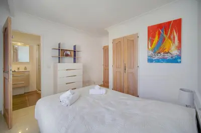a white bedroom with a bed and a painting on the wall at Lumineux 3 chambres TERRASSE PISCINE PARKING A3B134 in Cannes