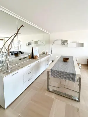 a kitchen with white cabinets and a table at Vue mer - Pointe Croisette - 1 chambre Spacieuse in Cannes