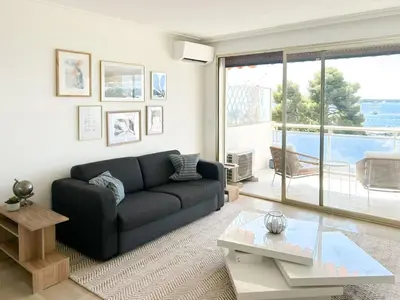a living room with a black couch and a table at Vue mer - Pointe Croisette - 1 chambre Spacieuse in Cannes