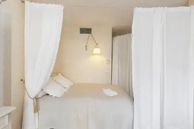 a small bedroom with white curtains and a bed at CG Armenonville White in Cannes