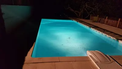 a blue swimming pool at night with a chair in it at Villa Super Cannes avec vue mer in Vallauris