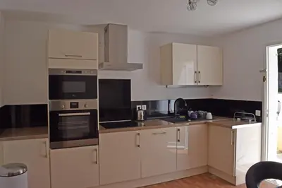 a kitchen with white cabinets and black appliances at Villa Super Cannes avec vue mer in Vallauris
