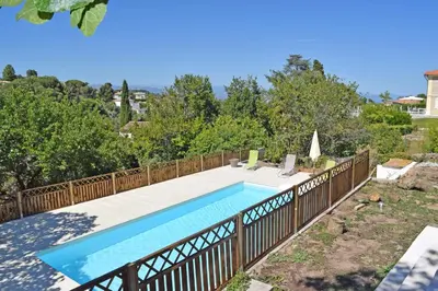 a swimming pool with a wooden fence around it at Villa Super Cannes avec vue mer in Vallauris