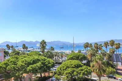 a view of a city with palm trees and a harbor at REF 1238 - Cannes Croisette - Sea view apartment for rent in Cannes