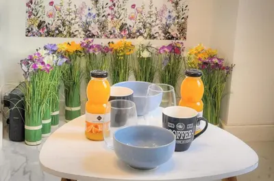 a table with two bottles and cups and flowers at Agréable Studio rue ANIBES-HYPER CENTRE A0B211 in Cannes