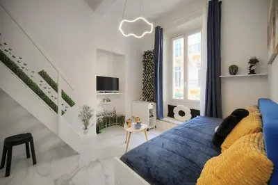 a white bedroom with a blue bed and a tv at Agréable Studio rue ANIBES-HYPER CENTRE A0B211 in Cannes